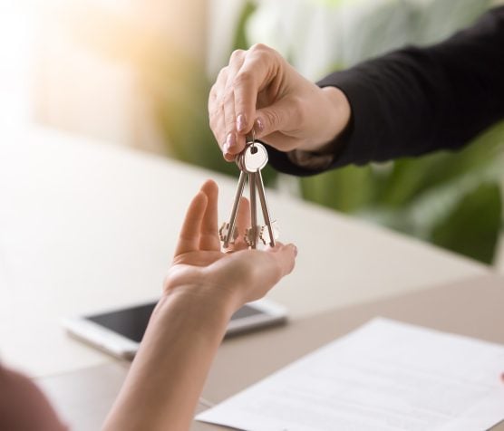 Young lady taking keys from female real estate agent during meeting after signing rental lease contract or sale purchase agreement. Independent woman purchasing new home, close up view